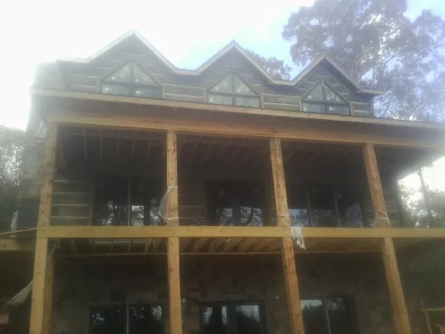 Dormers and porch framing on a large log home under construction — Roof Coating work by our crew in Buena Vista