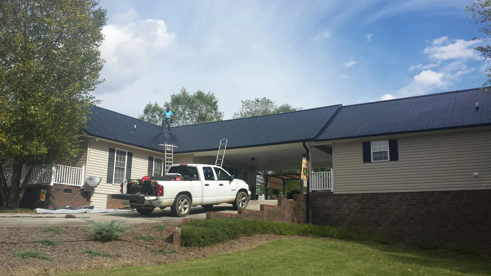 Black metal roof over a home and attached breezeway with ladders set in Buena Vista